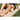 Person relaxes on mat using foam roller on leg in outdoor grassy area