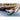 Person leg muscles stretch on foam roller outdoors on yoga mat