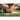 Woman uses foam roller on her back outdoors during a exercise session on a grassy area.